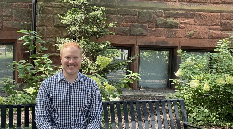 Ryan Martin, sitting on a bench in front of a brick building