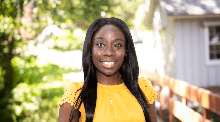 Amanda Awadey - a black woman wearing yellow and smiling - on the Mount Holyoke campus in 2023