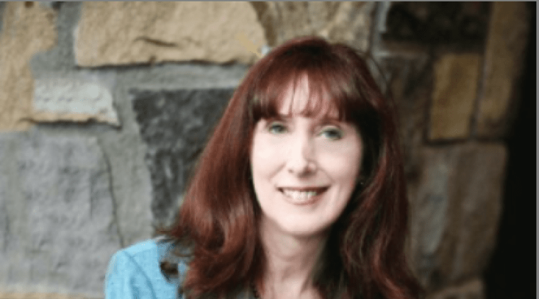 Katherine Bassett, wearing a blue jacket in front of a stone wall.