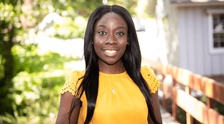 Amanda Awadey - a black woman wearing yellow and smiling - on the Mount Holyoke campus in 2023