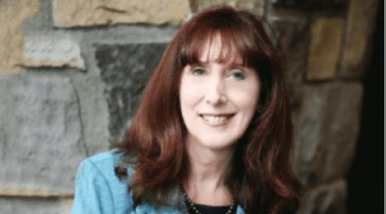 Katherine Bassett, wearing a blue jacket in front of a stone wall.