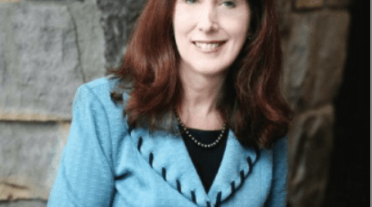 Katherine Bassett, wearing a blue jacket in front of a stone wall.