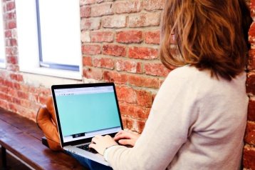 A student sitting on a bench working on a laptop