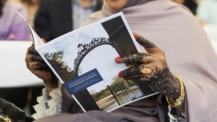 This is a phtograph of an attendee holding a program, with hands decorated in henna designs.