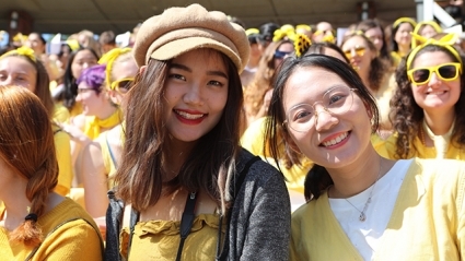 Incoming students in yellow grin under the sun at Convocation 2019.