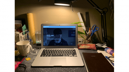 A laptop with "Reply 1994" playing on the screen.  A cup of tea sits nearby.