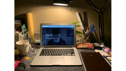 A laptop with "Reply 1994" playing on the screen. A cup of tea sits nearby.