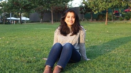 Minnal Abbasi on grass field with deep shadows behind her. The sun is going down.