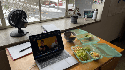 Lunch in a reuseable containter next to a laptop on a student desk