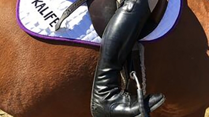 Close-up image of a riding boot in a stirrup
