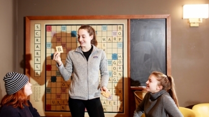 Photo of three students playing Scrabble on the large board in the Community Center