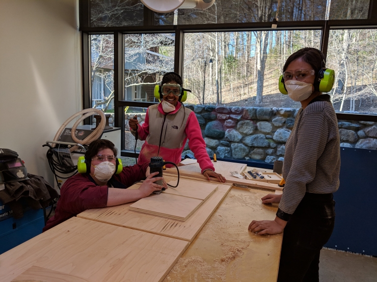 Three students working on sanding the pieces for the Fimbel reception desk.