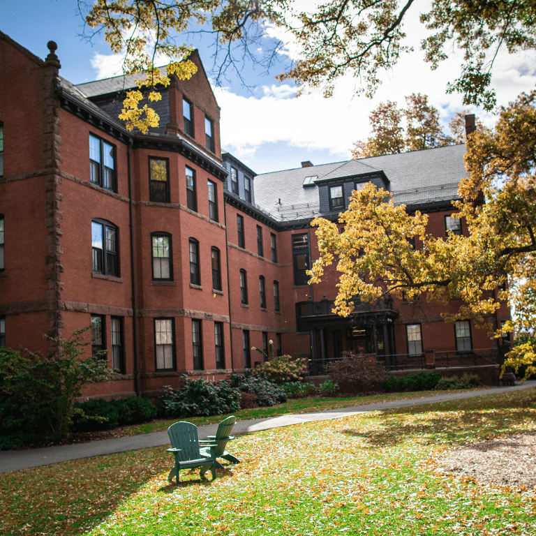 A pair of adirondack chairs outside of a residence hall on the Mount Holyoke College campus