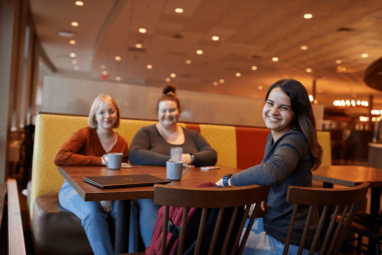 Three students seated together in the Mount Holyoke College Dining Commons