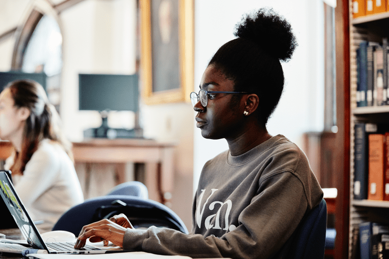 Student looking at a computer screen in the library.