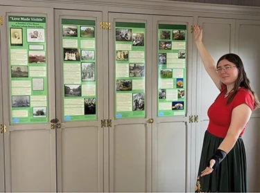 Barbara Wilkins ’28, gestures to a board with information about the plants housed in the Botanic Garden.