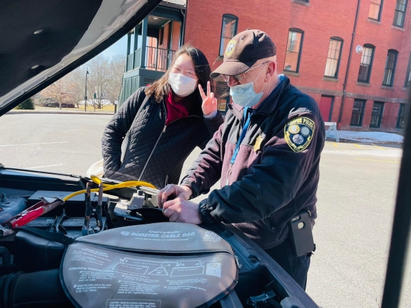 A student learning some vehicle maintence tips from a public safety officer