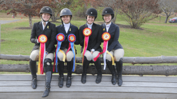 Four riding students sitting on a fencepost displaying their ribbons.