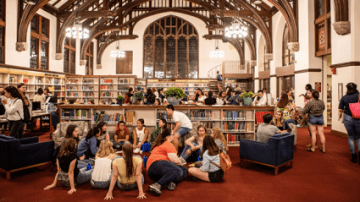 Students sit in groups in the library awaiting one of their first traditions - M&Cs.