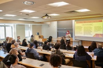 A student presenting in front of a lecture hall during Senior Symposium