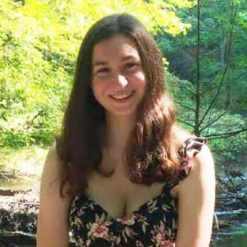 Nicole Tripp standing in a wooded area and smiling
