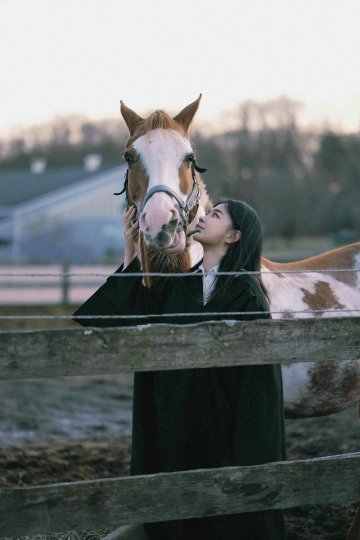 Lingdang Zhang ’24 with a horse at the Equestrian center field