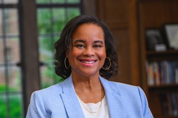 Danielle R. Holley, President of Mount Holyoke College in light blue in a library setting with windows behind her.