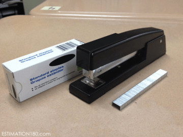 Photo from estimation180.com - a photo of a black stapler, with a stripe of staples next to it for estimation
