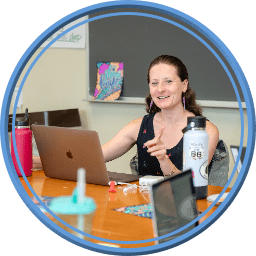 Public Schools Leadership: A teacher at a desk with a laptop looking at a classroom.