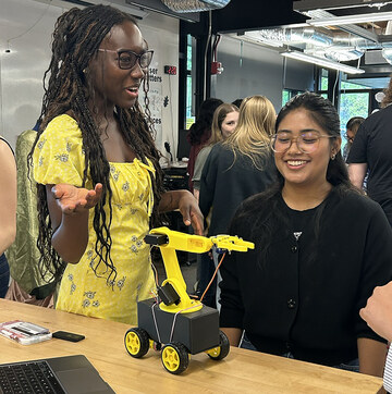Students Adwoa Owusu ’26 (left) and Sadichchha Maharjan ’26 (right) show off Marcus (center), their personal assistant robot.
