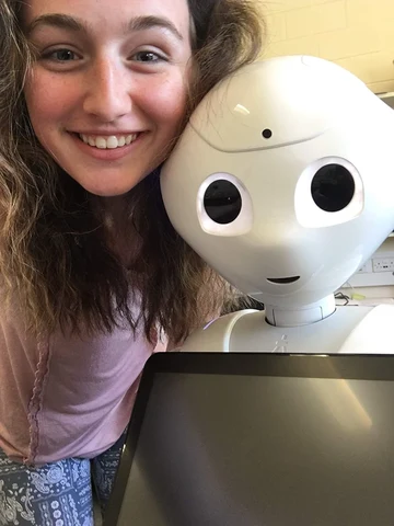 Emilyann Nault ’19 poses with a robot during a Lynk-funded internship in human-robot interaction at Heriot-Watt University, Scotland, 2018.