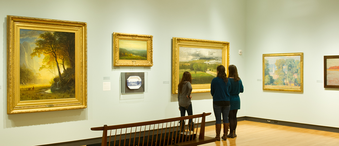 Three students looking at art in a gallery.