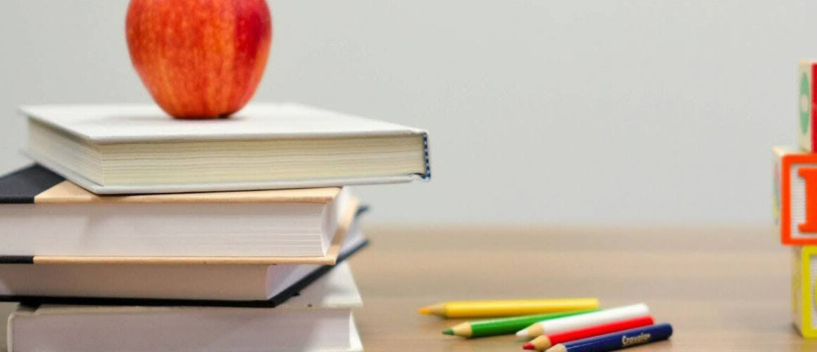 Teacher’s desk with books, blocks, colored pencils and an apple.