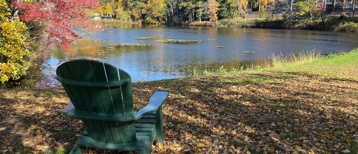 Lower lake in the fall with an Adirondack chair looking out over the water.