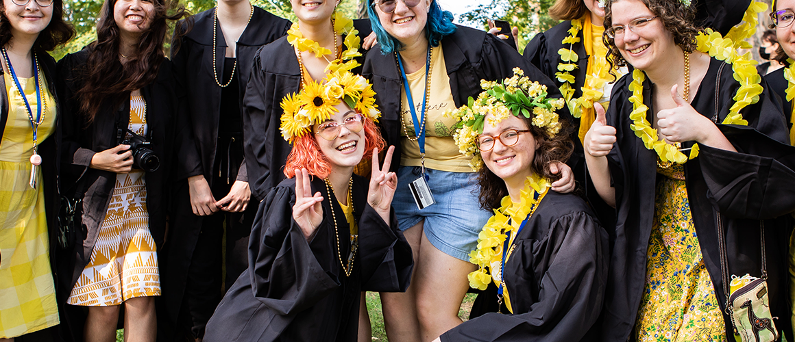 A group of seniors in their graduation robes with yellow clothing underneath ready for Convocation 2022