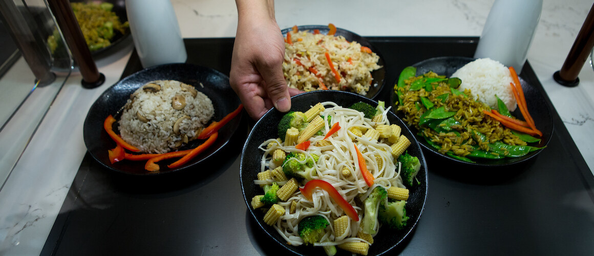 Four bowls of food from the dining hall, includes rice and vegetables.