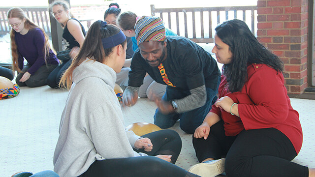 Guest artist Mohammed Alidu, center, demonstrates a rhythm on the calabash to students.