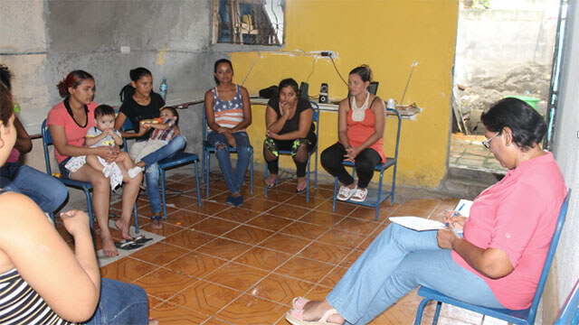 A group of you mothers gather inside the community center to work with a psychologist.