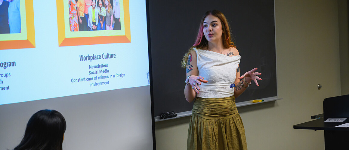 LEAP Symposium presenter in front of a screen with presentation, October 2024