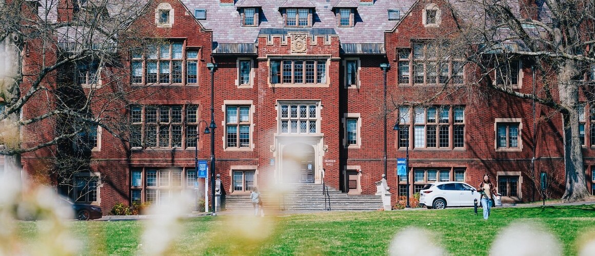 Skinner Hall on Mount Holyoke Campus, with blooms and greenery in the foreground.