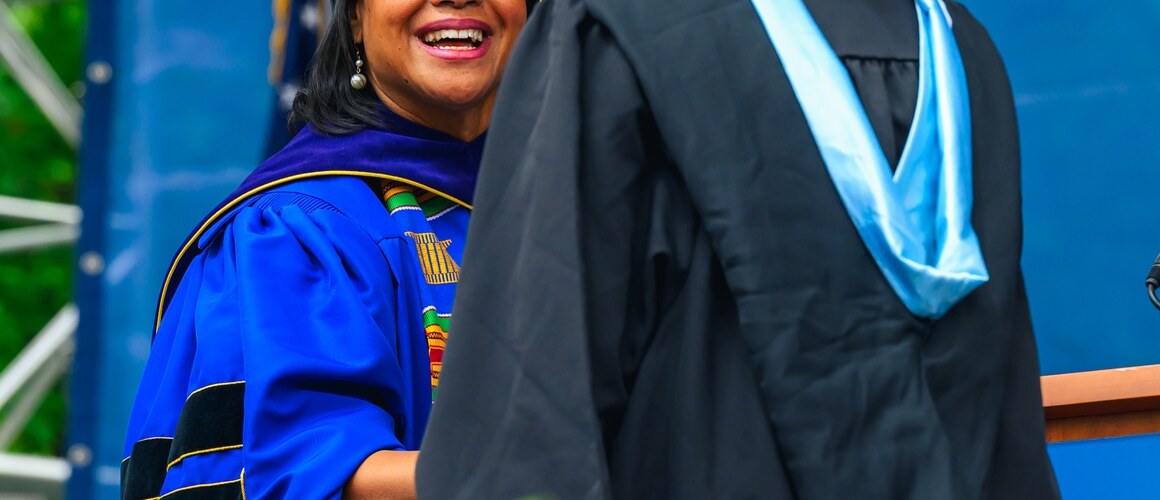 President Holley shakes hand of new graduate, Commencement 2025.