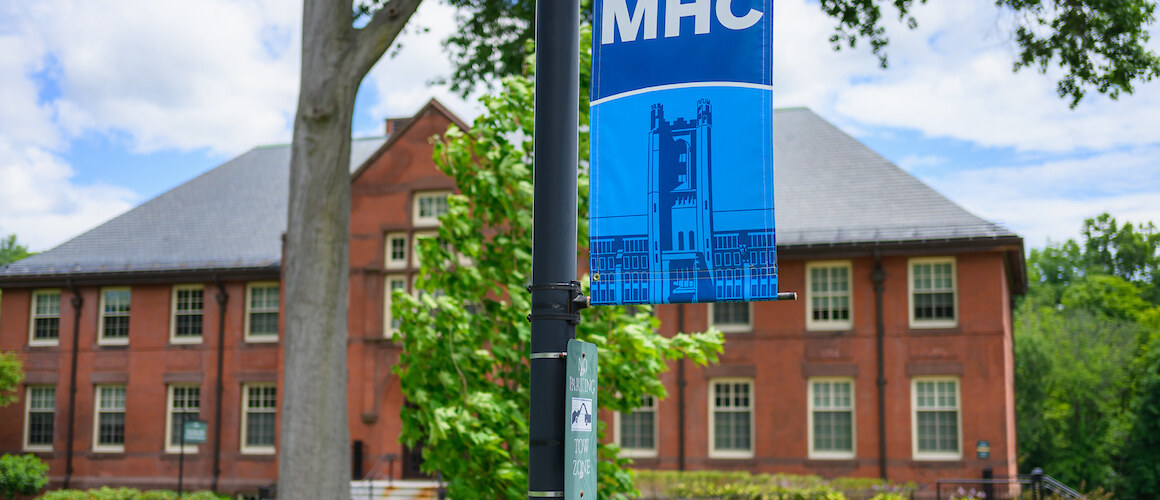 Mount Holyoke banner flies on a lightpost on campus.