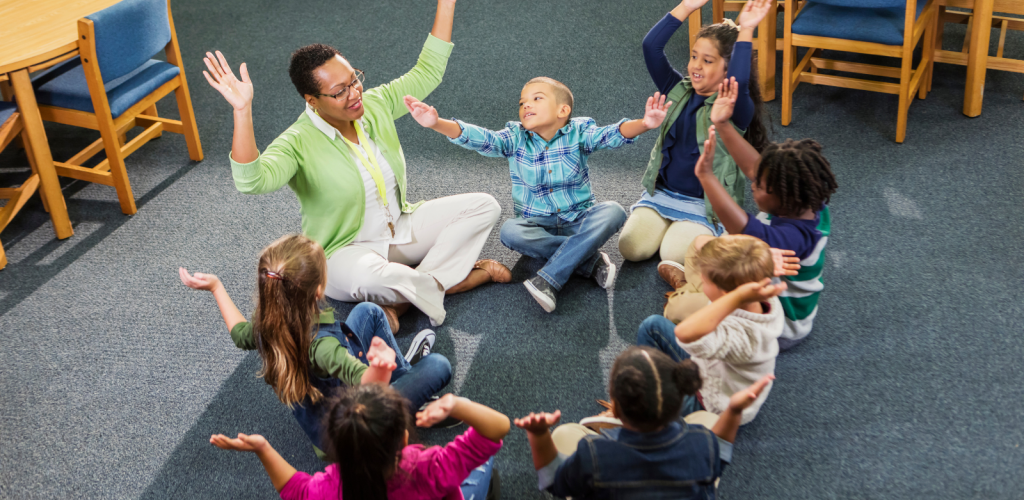Engaged students in a circle raising arms with their teacher.