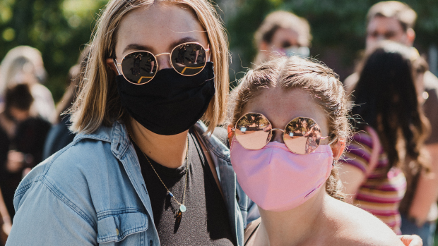 Two students pose together wearing masks.