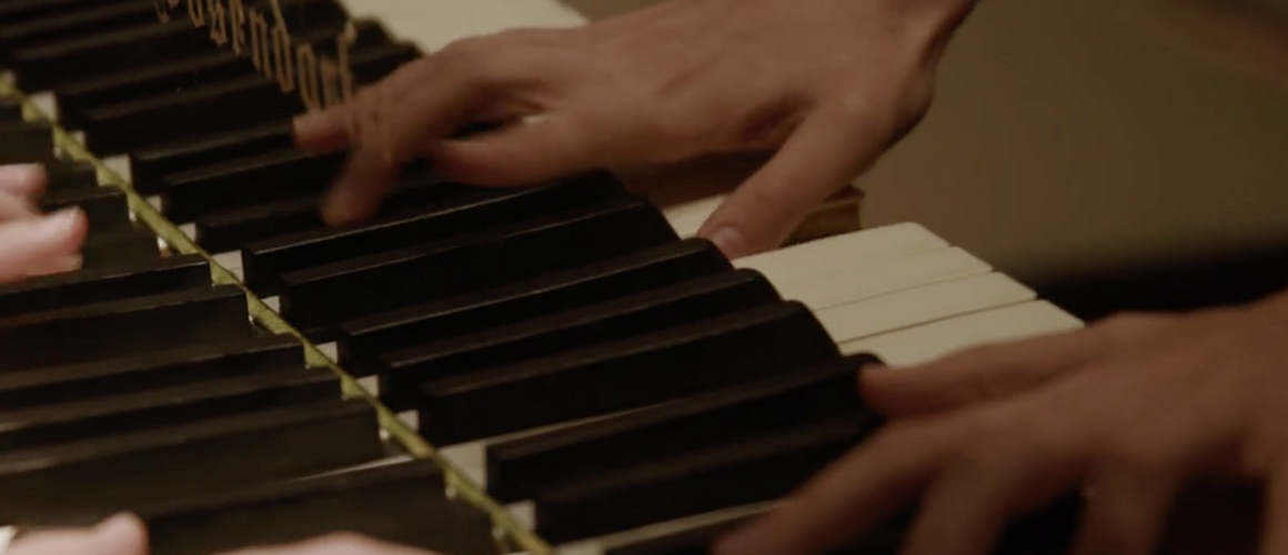 A close-up of a student's hands playing the piano