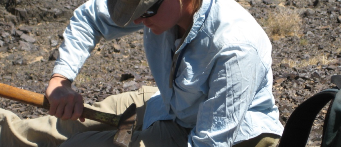Rita C. Economos ’01 chiseling rock in the field.