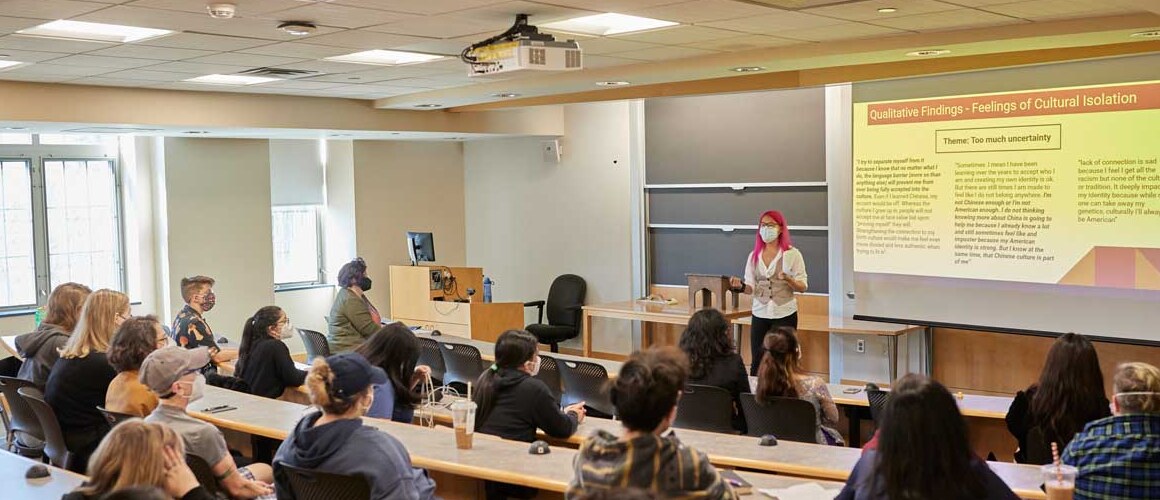 A student presenting in front of a lecture hall during Senior Symposium