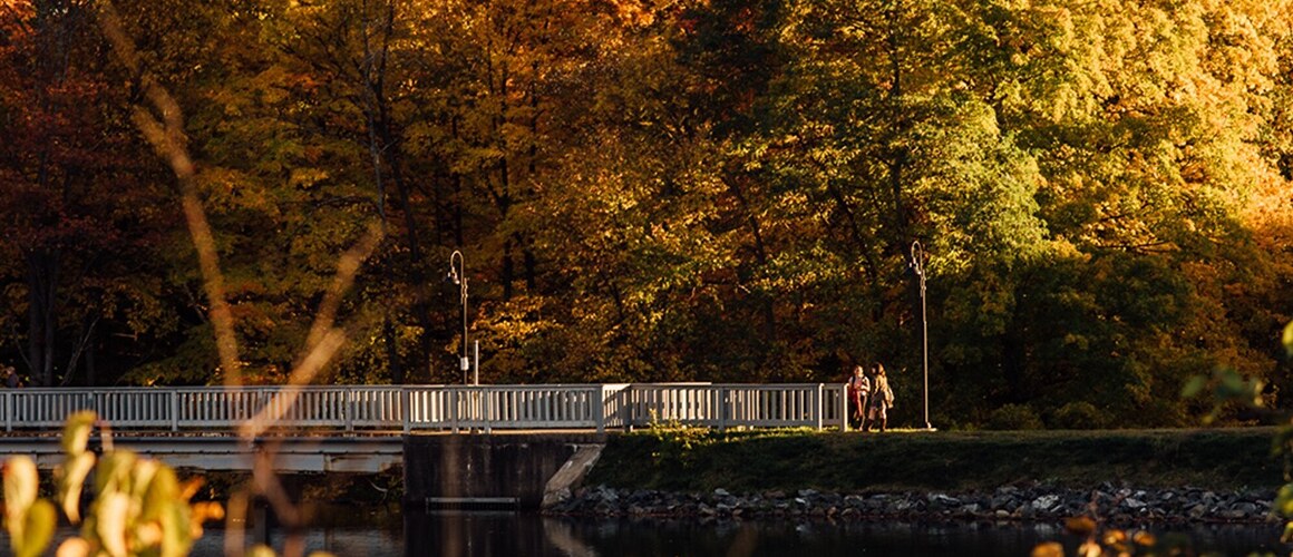 Students crossing the Lower Pond bridge in fall.