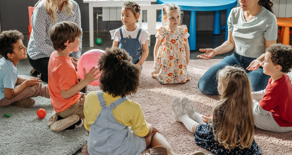 Young students sitting in a circle with teachers.
