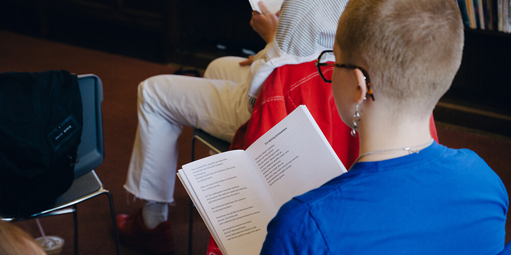 A person in an audience looking at a book.